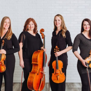 Elegant string quartet performing live at a wedding ceremony, featuring violinists, violist, and cellist in a classic setting.