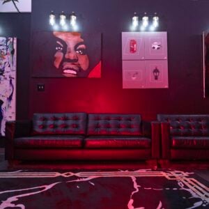 Modern art and coffee lounge with leather sofas, vibrant red lighting, and expressive wall art — a stylish space for live music, art shows, and creative gatherings.