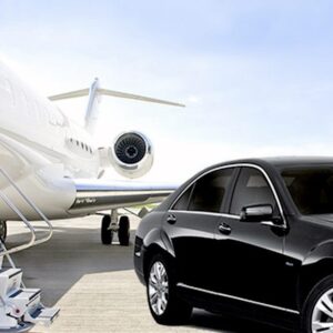 Luxury black car parked beside a private jet on an airport runway, representing premium transportation services.
