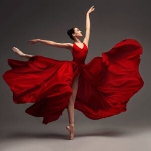 Graceful ballet dancers performing on stage in elegant costumes under soft, dramatic lighting.