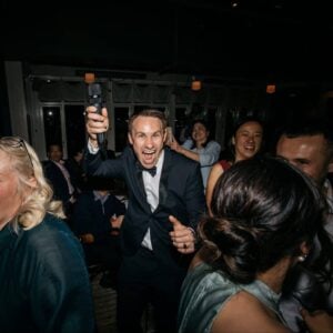 Professional event emcee and officiant engaging with guests during a celebration, creating a lively and heartfelt atmosphere.