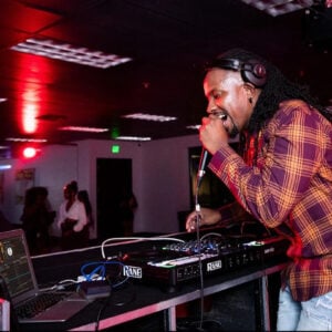 Professional DJ performing live with a sound engineer managing audio levels at a mixing console.