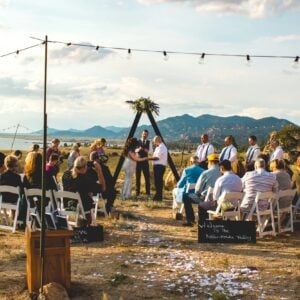 Intimate wedding ceremony setup with floral arch, elegant table décor, and romantic outdoor lighting.